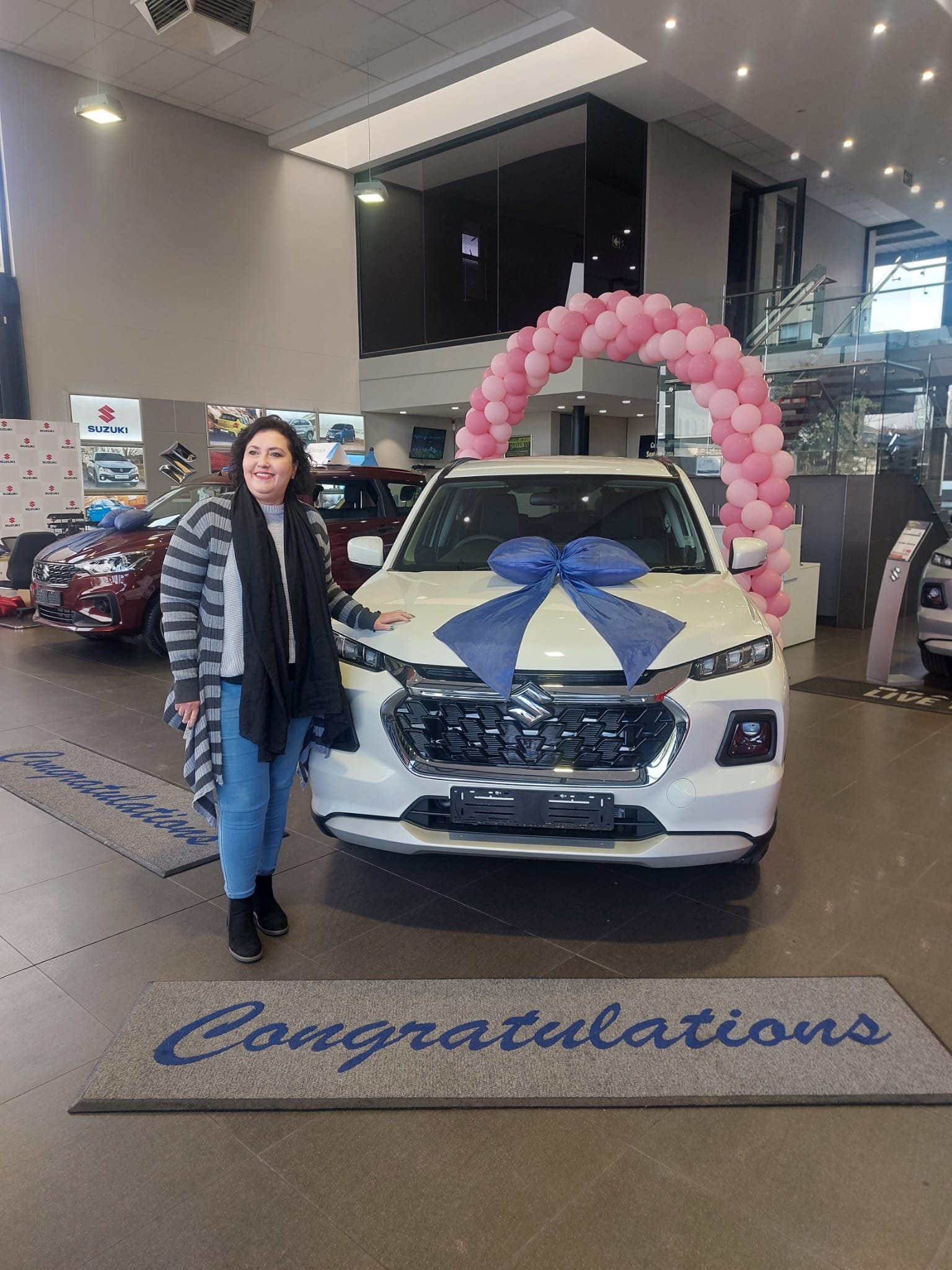 Client collecting her white Suzuki SUV at the dealership